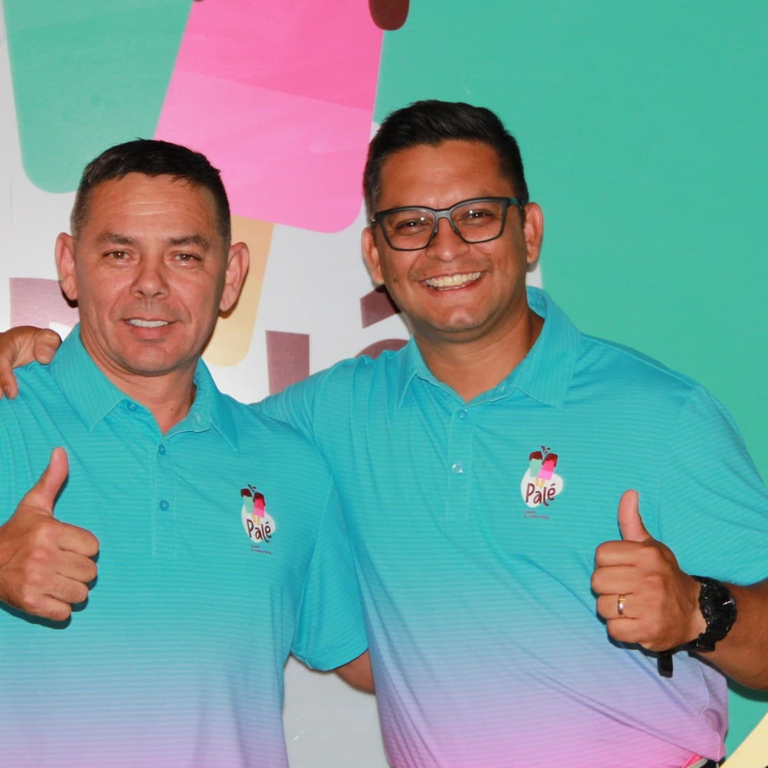 Elder and Alejandro, in matching teal Palé polos, giving a thumbs-up in front of the Palé logo